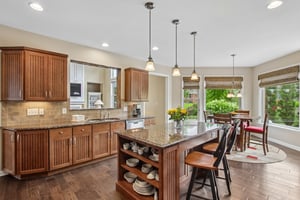 Center island offers open shelving and bar seating with pendant lighting