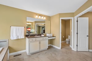 View of the Primary Bathroom Suite with private water closet, separate vanities, deep soaking tub, and large custom tiled shower