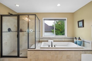 View of the custom tiled shower and deep soaking tub in the Primary Bathroom