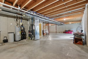 Unfinished lower level showing mechanicals area and large open space with 2 egress windows and plumbed for a full bathroom, and wet bar