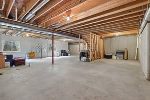 View of the unfinished lower level - 2 egress windows, plumbed for full bathroom, and wet bar