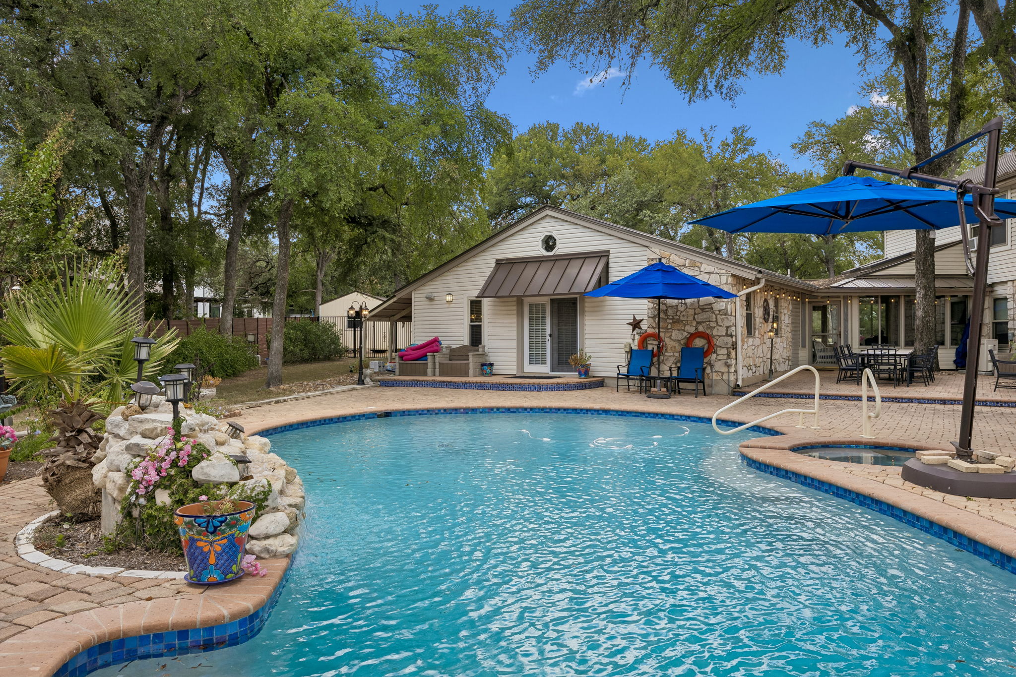 Resort style pool with waterfall and hot tub.