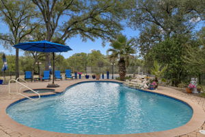 An inviting backyard oasis awaits with a sparkling pool and spa, set on a paver patio amidst mature trees.