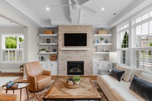 Family room with coffered ceilings, built in cabinets, floating shelfs, ceiling speakers with Sonos system, and gas fireplace with brick surround